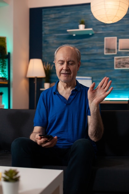 Portrait of elderly man waving for video call conference