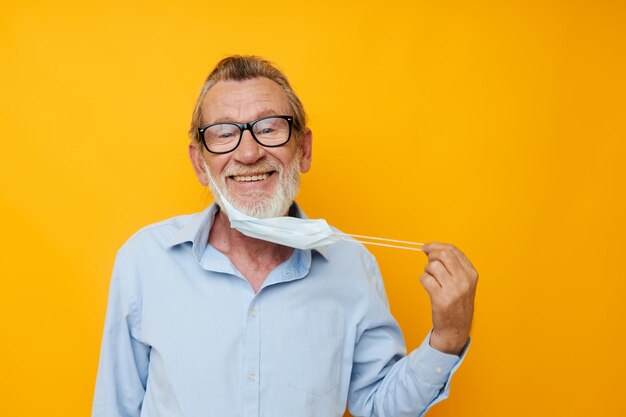 Portrait elderly man with glasses safety medical mask posing yellow background