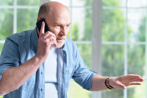 Portrait of a elderly man with phone at home