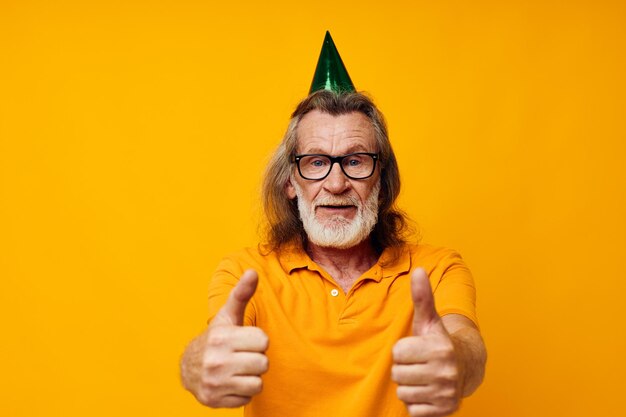 Portrait elderly man in a yellow tshirt with a cap on his head fun yellow background