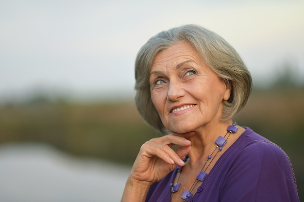 Portrait of a elderly woman  in  summer near lake