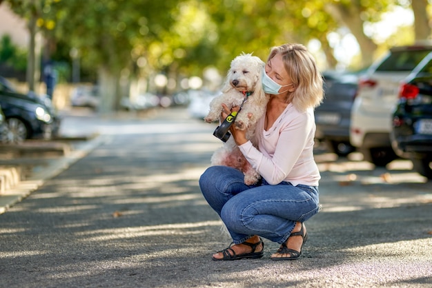 屋外で犬を連れた年配の女性のポートレート、ウイルス対策マスク