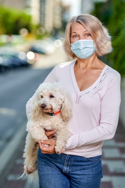 Portrait elderly woman with a dog outdoors an antivirus mask.