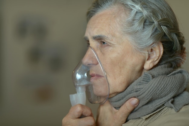 Foto ritratto di donna anziana con inalazione di influenza