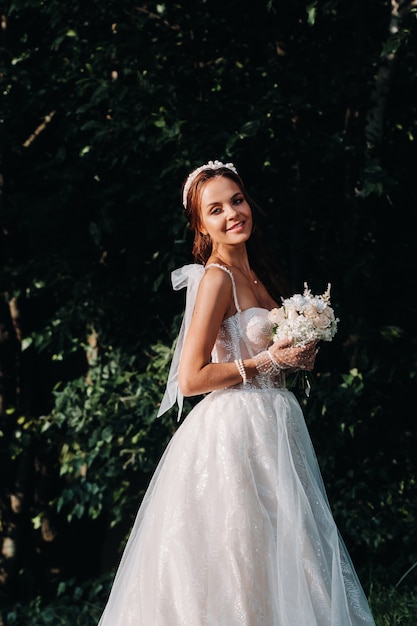 Portrait of an elegant bride in a white dress with a bouquet in nature in a nature Park.Model in a wedding dress and gloves and with a bouquet .Belarus