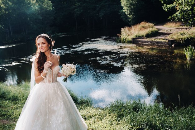 Портрет элегантной невесты в белом платье с букетом на природе в природном парке.