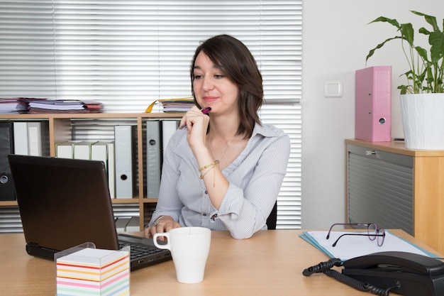 Portrait of an elegant businesswoman with laptop in a bright office