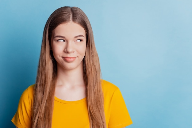 Portrait of elegant magnificent girl look side empty space on blue wall