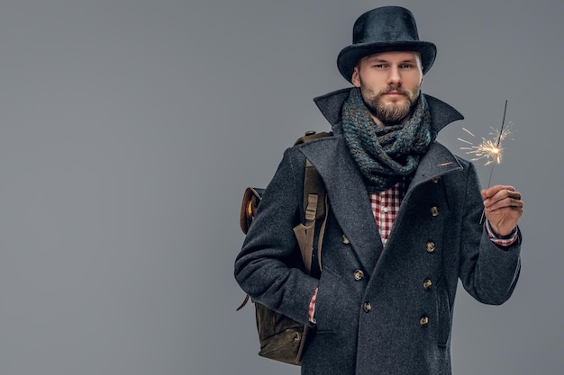 Ritratto di un uomo elegante vestito con una giacca grigia e un cappello a cilindro isolato su sfondo grigio.