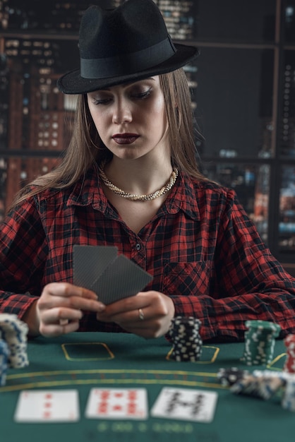Portrait of elegant stylish young woman with card and casino chips play poker game