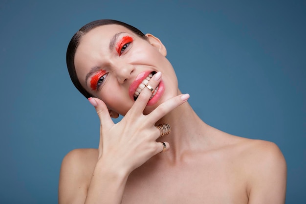 Portrait of an elegant young woman with red bright makeup on a blue background. Beauty fashion