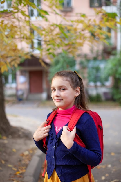 Portrait of elementary school student with red briefcase on autumn da