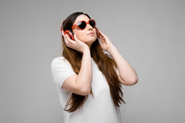 Portrait of emotional beautiful plus size model in headphones and sunglasses standing looking away 