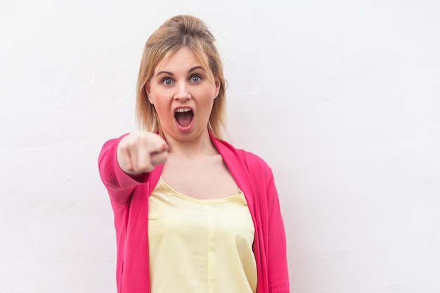 Portrait of emotional blonde woman standing near white wall