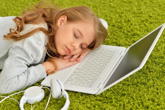 Portrait of emotional cute girl sleeping near laptop