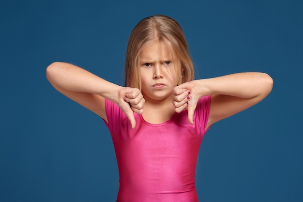 Portrait of emotional expressive little girl on blue background