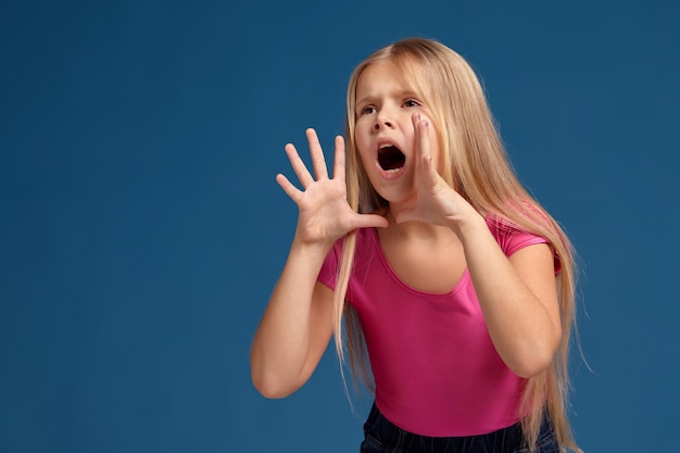 Photo portrait of emotional little girl on blue background