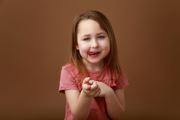 Portrait of emotional preschool girl showing tongue