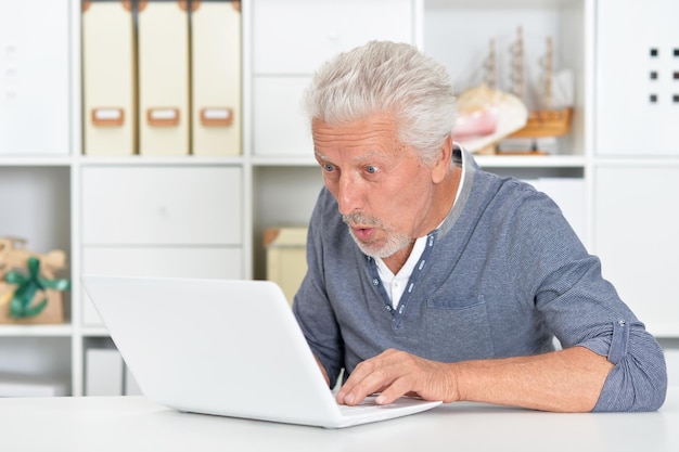 Portrait of emotional senior man using laptop