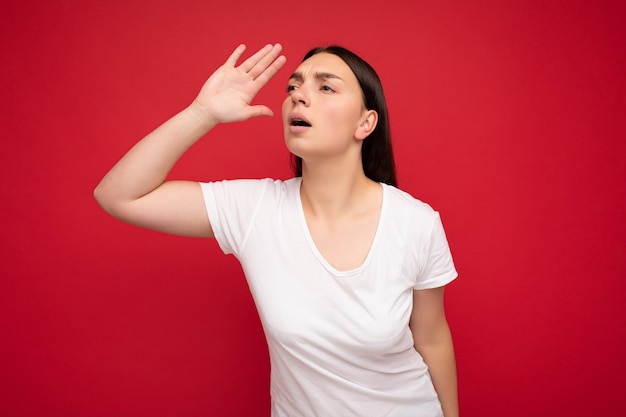 のための白いTシャツを着て誠実な感情を持つ感情的な若い美しいブルネットの女性の肖像画