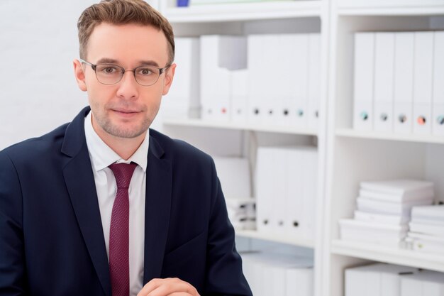 Portrait of an employee of an accounting office man in glasses and navy blue suit