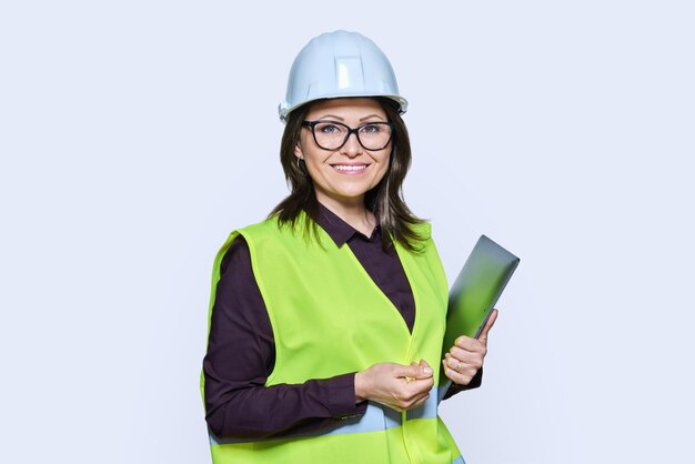 Portrait of engineer manager woman in helmet vest holding laptop over white studio background Logistics construction industry management architecture engineering staff workers concept