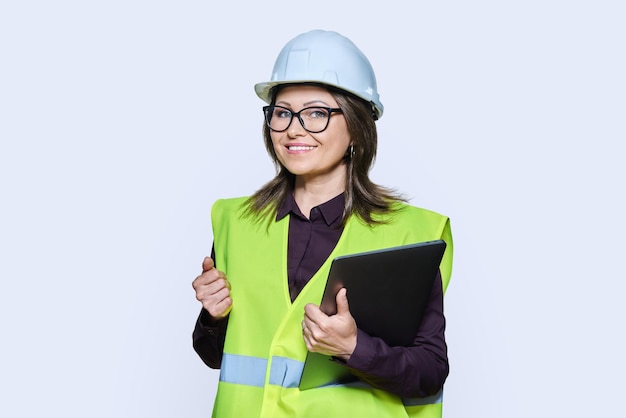 Photo portrait of engineer manager woman in helmet vest holding laptop