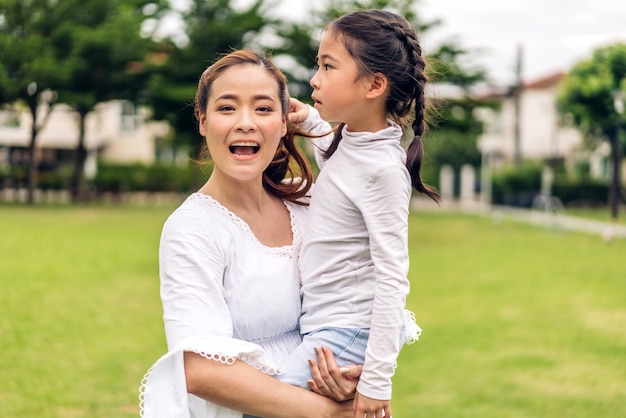 幸せな愛を楽しむの肖像アジアの家族の母と小さなアジアの女の子の子供が笑顔でかわいい子供の娘との抱擁を楽しんでいる楽しい時間