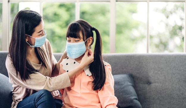 Portrait of enjoy happy love asian mother wearing protective mask for little asian girls child in quarantine for coronavirus with social distancing at home