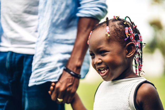 Portrait of enjoy happy love black family african american father holding little african girl hand in moments good time in summer park