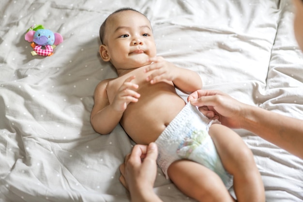 Portrait of enjoy happy love family asian mother playing with adorable little asian babyMom touching with cute son moments good time in a white bedroomLove of family conceptx9