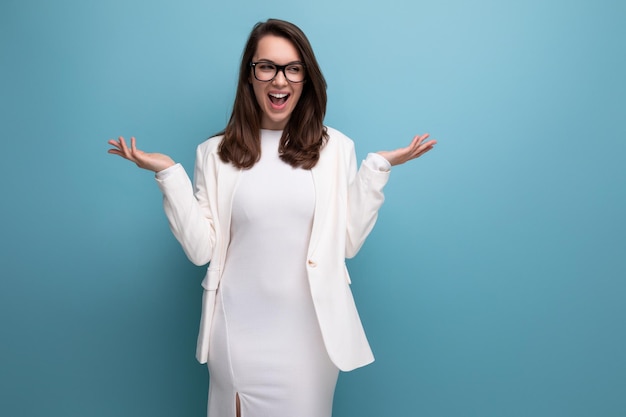 Portrait of a european young woman in a white office dress with glasses on a blue background with