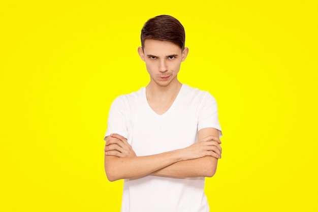 Portrait of evil guy in white t-shirt isolated on yellow background.