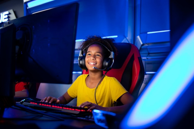 Portrait of excited african american girl with headset playing\
video games on computer in game room