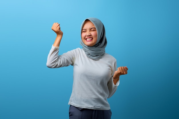 Portrait of excited Asian woman celebrating success with raised arms