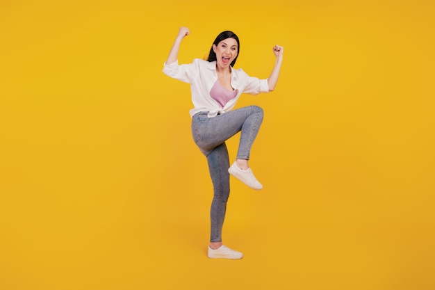 Portrait of excited astonished girl celebrate victory success on yellow background