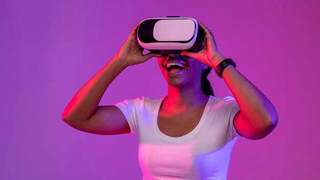 Portrait of excited black woman wearing vr headset in neon light