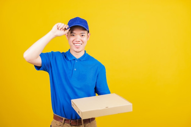 Portrait excited delivery service man standing he smile wearing blue tshirt and cap uniform hold give food order pizza cardboard boxes looking to camera studio shot isolated on yellow background