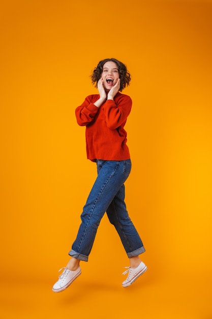 portrait of an excited emotional happy young pretty woman posing isolated over yellow wall.