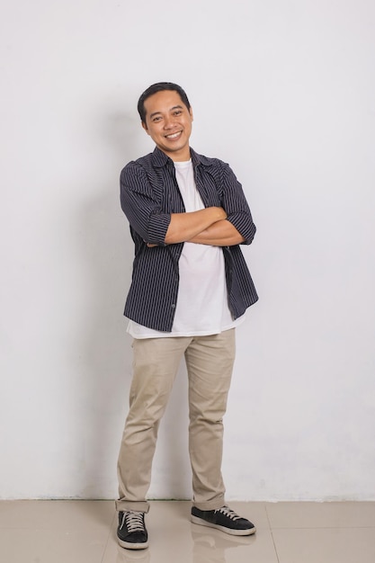 Portrait of excited handsome asian man in shirt smiling and crossing arms at camera