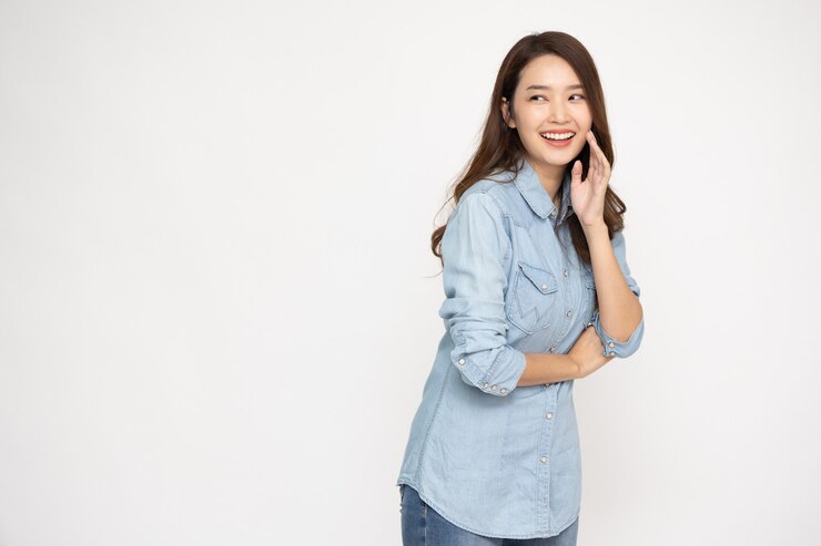 Photo 흰색 배경에 격리된 진 셔츠를 입은 흥분된 행복한 젊은 아시아 여성의 초상화