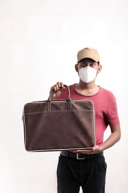 Portrait of a excited happy young delivery man in cap standing over white background and holding bag in hand.