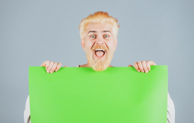 Portrait of excited man showing blank signboard with copyspace area for slogan or text young funny m