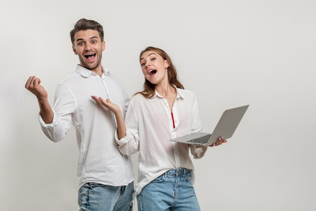 Portrait of excited man and woman holding laptop isolated over white background