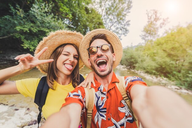 Photo portrait of excited man and woman wearing hat against trees