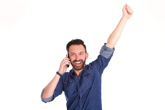 Portrait of excited mature man talking on mobile phone and laughing with his hand raised i