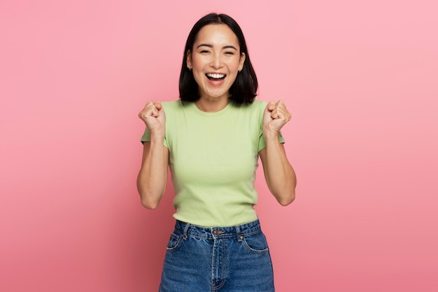 Portrait of excited overjoyed woman standing with raised fists and shouting yeah