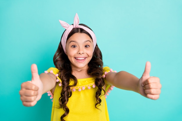 Portrait of excited positive child girl show thumb up sign