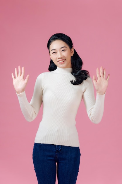 Portrait of excited screaming young asian woman standing isolated over pink background