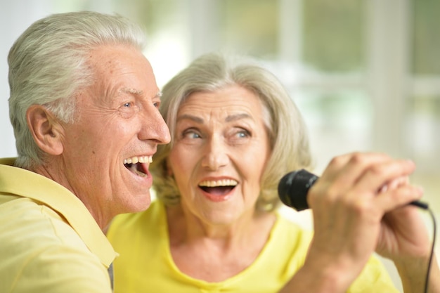 Portrait of a excited senior couple singing in microphone